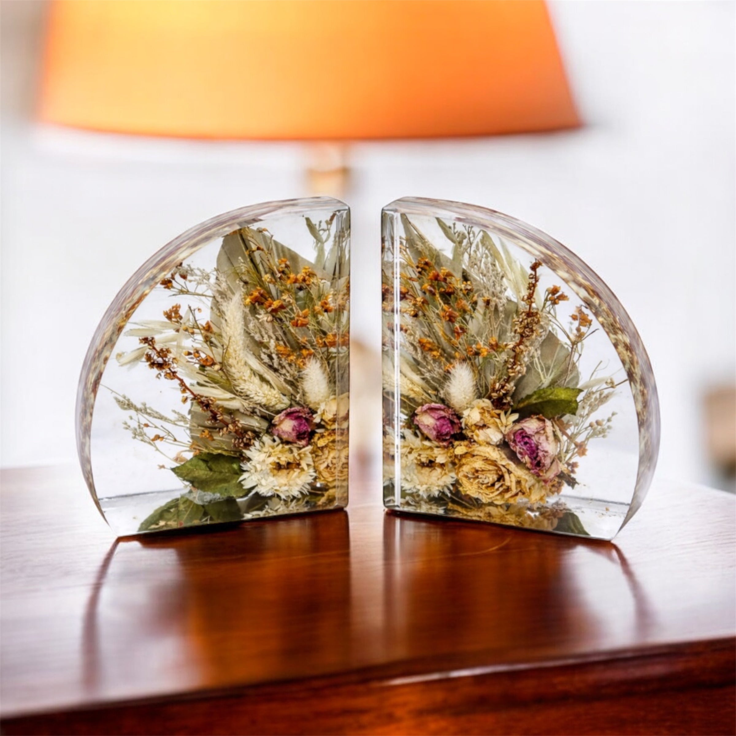 Crystal-clear resin bookends with preserved dried flowers placed on a table.