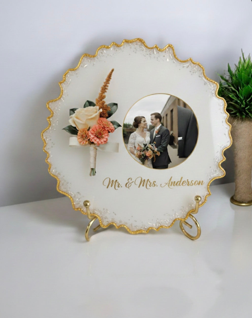 Round resin frame with a photo of a couple and flowers (boutonnières) , personalized with 'Mr. & Mrs. Anderson'.